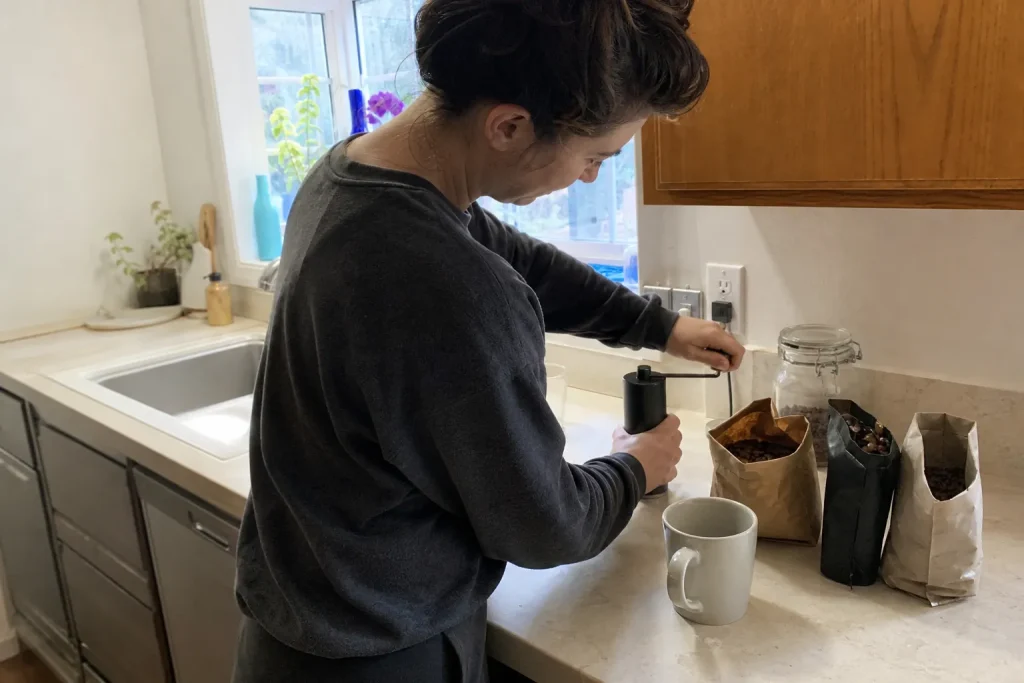 Person mal kaffebönor för hand i köket, ett steg som påverkar kaffe smak kvalitet i koppen.
